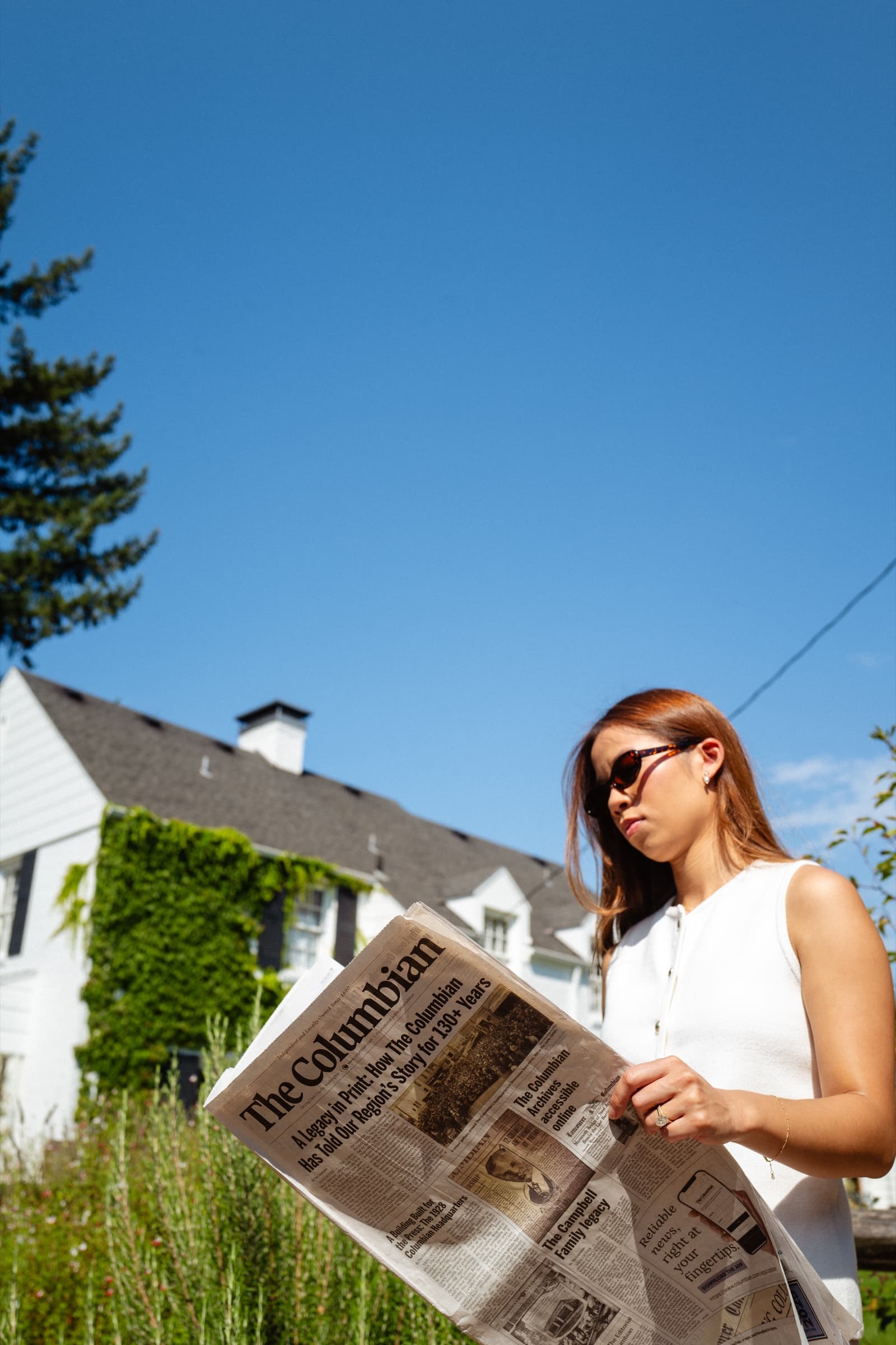 Woman reading The Columbian outside a house