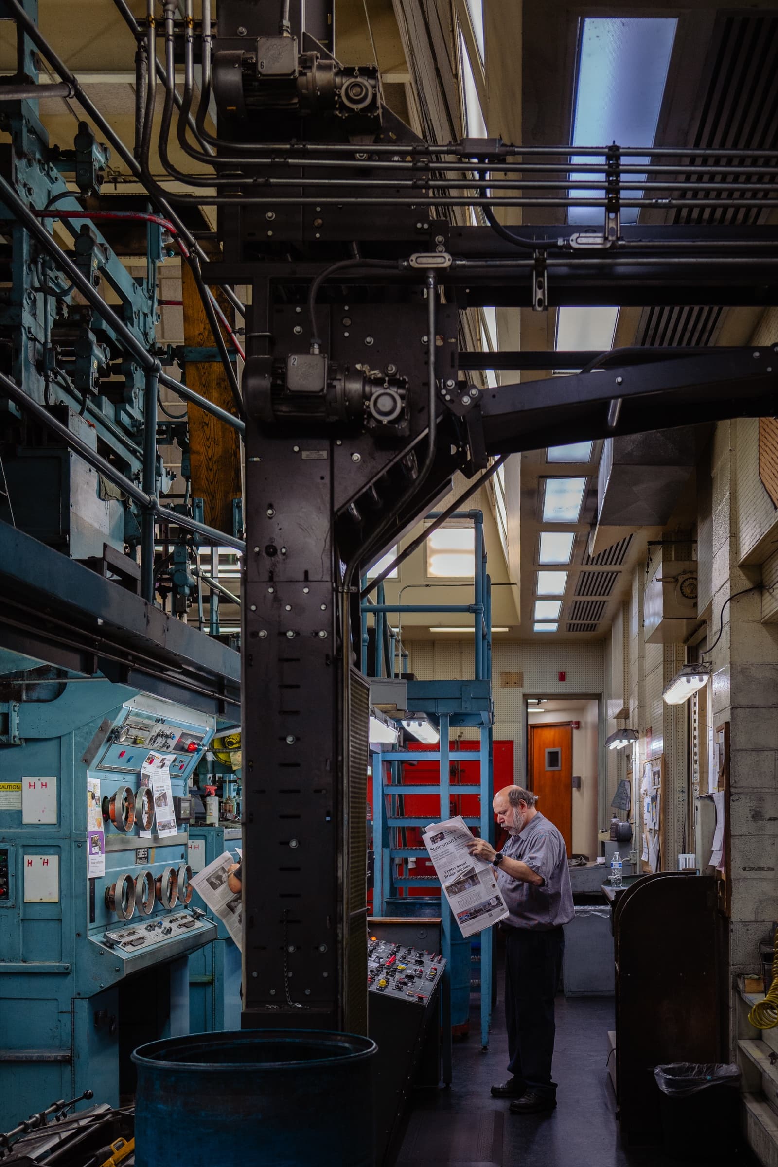 Man reading The Columbian inside the printing press facility