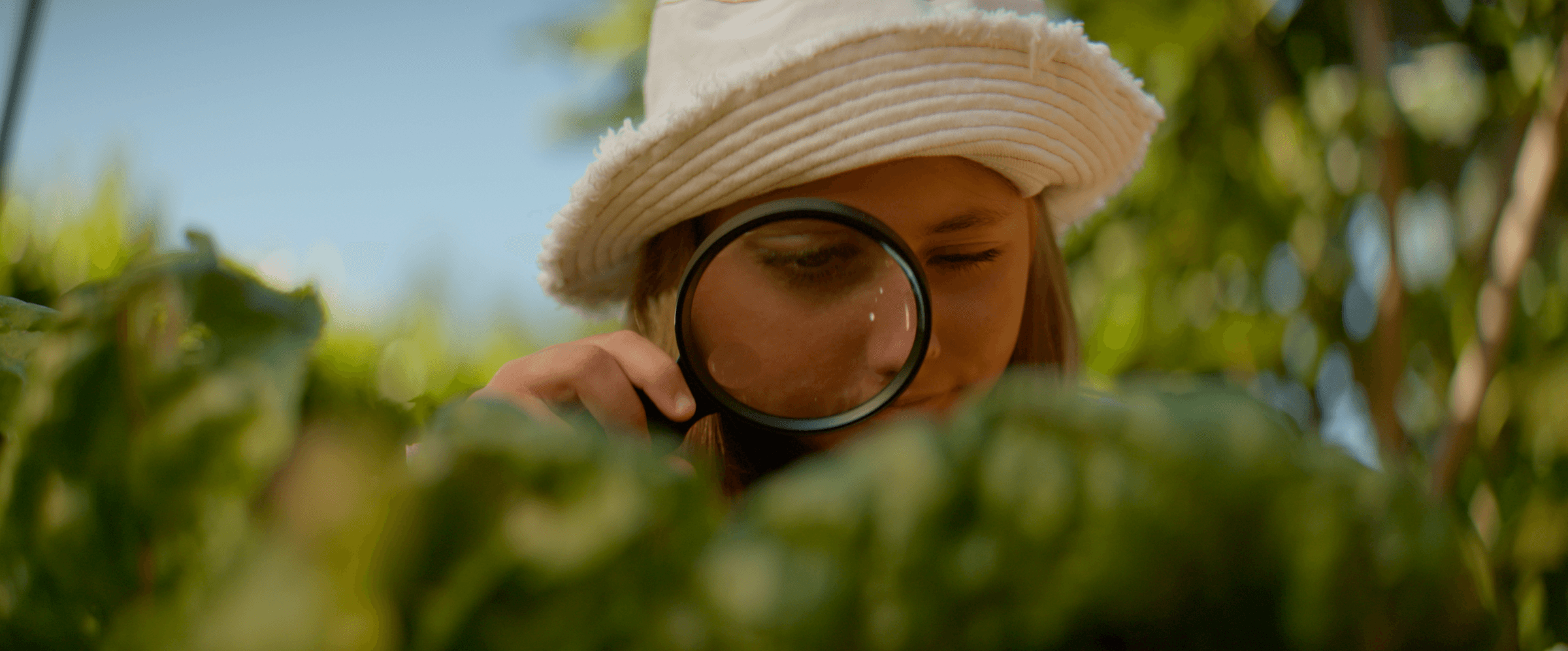 Girl with magnifying glass in garden
