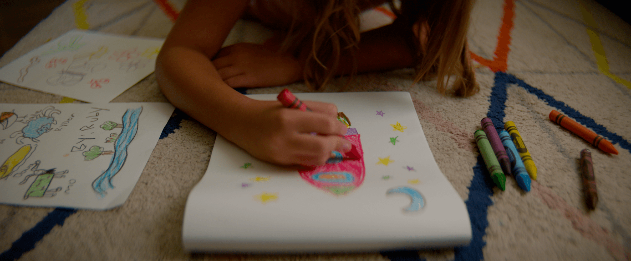 Girl drawing with crayons on the floor