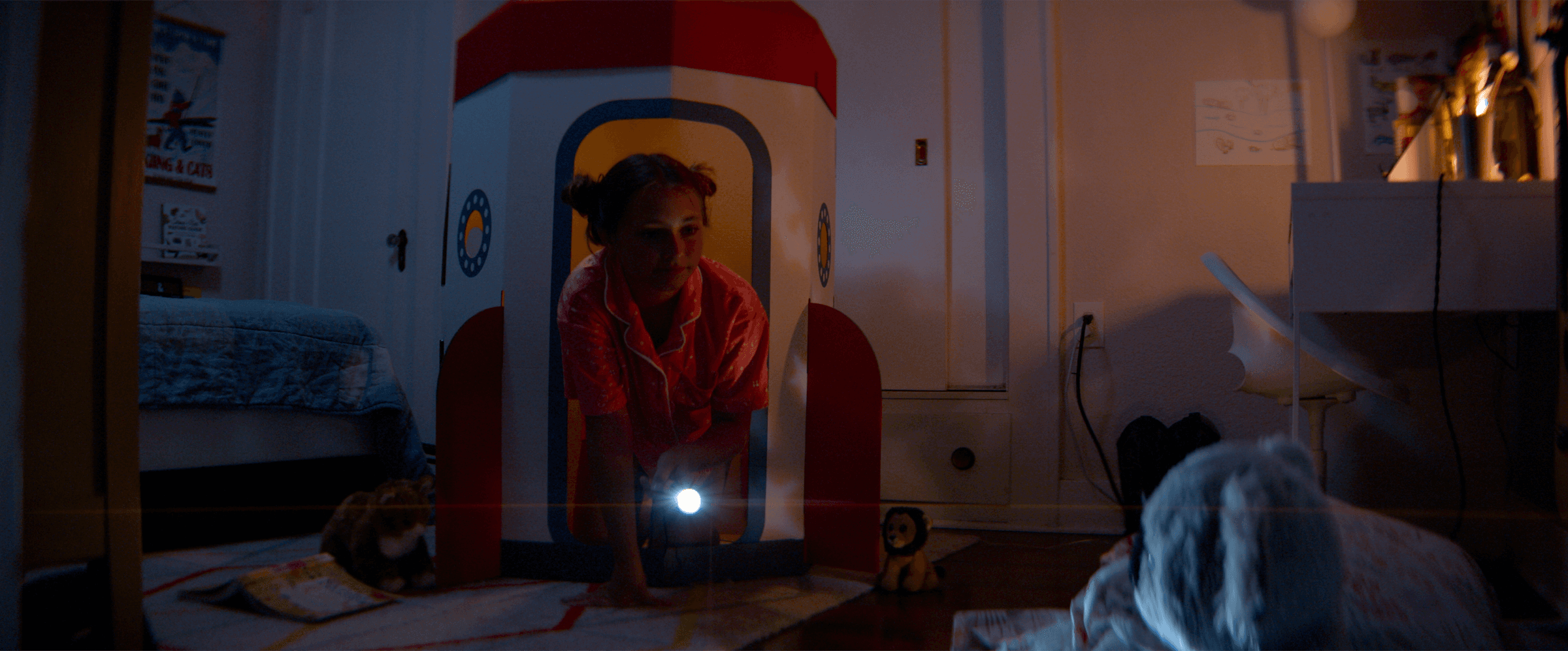 Figure in rocket ship playhouse with flashlight